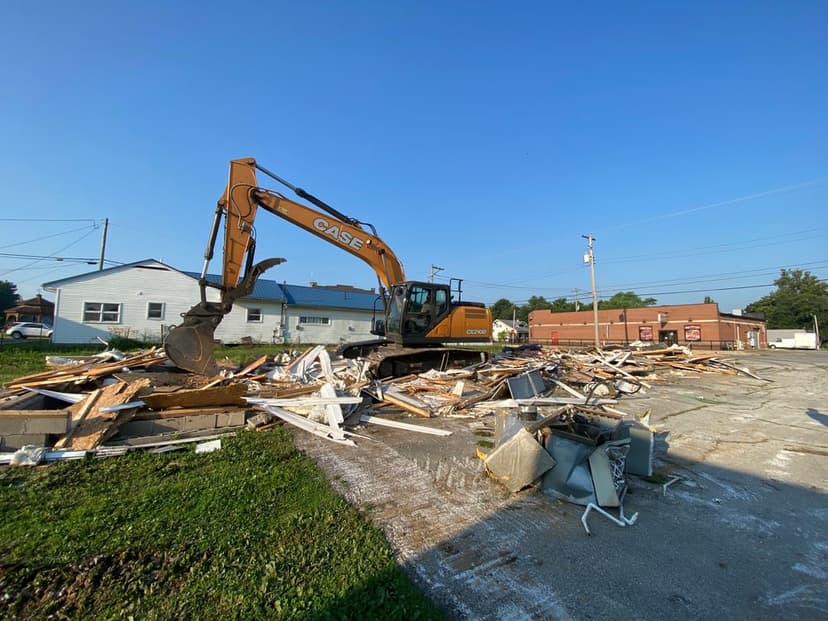 Excavator demolishing debris and construction materials at a building site.