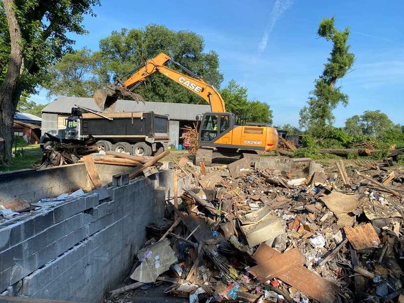 Heavy machinery demolishing debris at a construction site on a clear day.